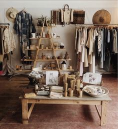 a room filled with lots of clothes and items on shelves next to a wooden table