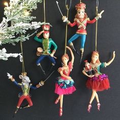 four ornaments are hanging from strings in the shape of people on skis and snowboards