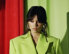 a woman in a lime green suit standing next to a red and green curtain with her hands on her hips