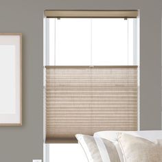 a bedroom with a window covered in blinds and pillows