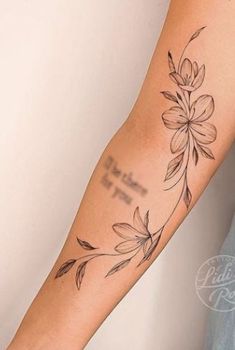 a woman's arm with flowers and words tattooed on the side of her arm