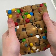 someone is holding up a cookie with m & m on it's top and bottom