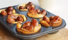 a muffin tin filled with mini pigs in a blanket next to a cup of milk