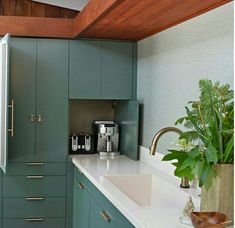 a kitchen with green cabinets and white counter tops, along with a coffee maker on the wall