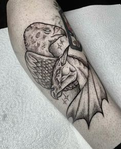 a black and white tattoo on the leg of a man with an owl and dragon