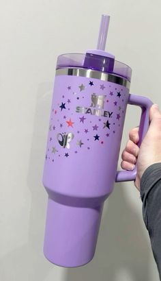 a person holding a purple tumbler cup with stars on it and the words stay cozy