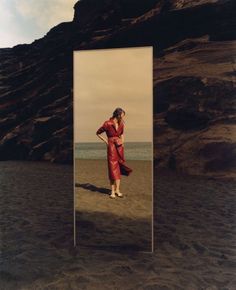 a woman standing in front of a mirror on the beach