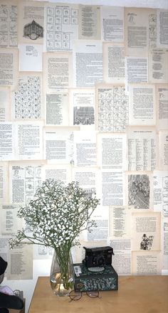 there is a vase with flowers and an old typewriter in front of the wall