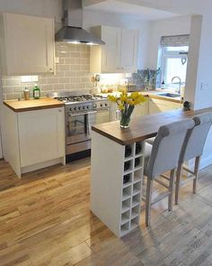 a kitchen with white cabinets and wooden floors is pictured in this image, there are four chairs at the counter