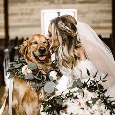 a bride kissing her dog on the cheek with greenery around it's neck