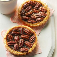 two pecan pies sitting on top of a table next to a cup of coffee