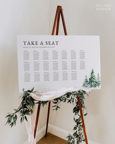 a seating chart on a easel with greenery