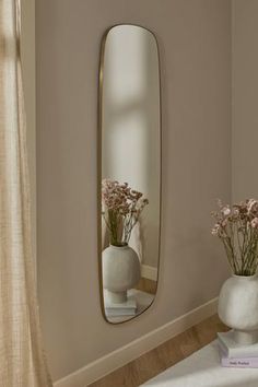 two vases with flowers are sitting in front of a large mirror on the wall