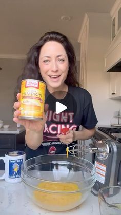 a woman holding up a can of food