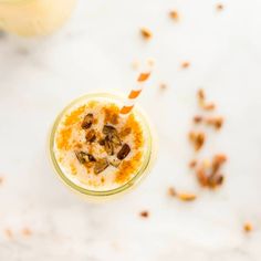 an overhead view of a smoothie in a glass with nuts on the rim and a straw sticking out of it