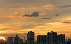 the sun is setting in front of some very tall buildings and skyscrapers on the horizon