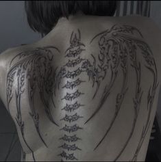 the back of a man with tattoos on his upper and lower back, which are intricately designed