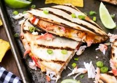 three quesadillas on a baking sheet with limes and other toppings