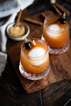 two glasses filled with drinks sitting on top of a wooden tray