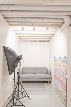 an empty room with a couch and camera set up in front of the couch on the floor