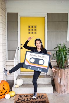 a woman in black shirt holding up a radio cassette costume on front of yellow door