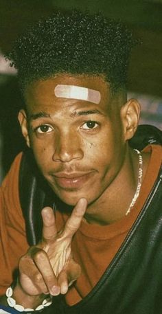 a young man sitting at a table with his finger up