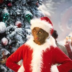 a man dressed as santa claus standing in front of a christmas tree