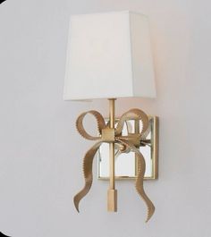 a wall light with a white shade on it's side and a beige ribbon wrapped around the lamp