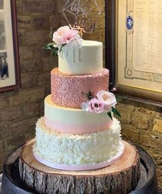 a three tiered cake sitting on top of a wooden table next to a brick wall