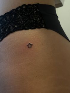 a woman's stomach with a tiny star tattoo on it