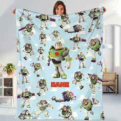 a woman holding up a personalized blanket with toy story characters on it