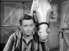 a man standing next to a white horse