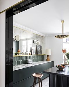 a kitchen with black cabinets and stools next to a counter top in front of a window