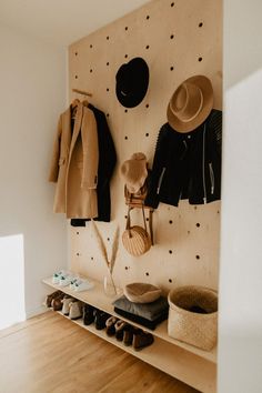 a coat rack with hats, shoes and coats hanging on it's side wall