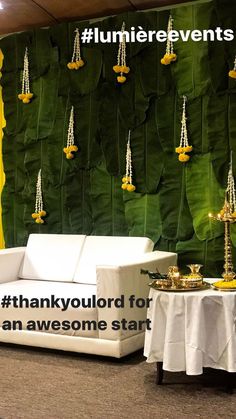 a white couch sitting in front of a green wall covered in hanging candles and chains