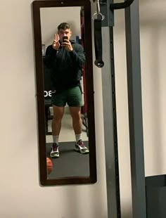 a man taking a selfie in front of a mirror with his reflection on the wall