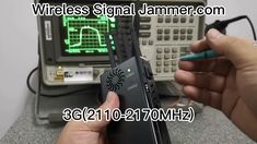 a person holding a cell phone in front of an electronic device with the words wireless signal jammer com on it