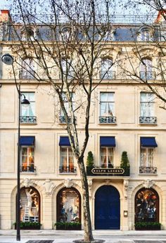 the building has many windows and blue shutters on it's front door, along with several trees