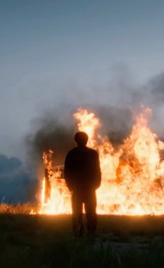 a man standing in front of a large fire