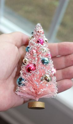 a pink christmas tree ornament in someone's hand