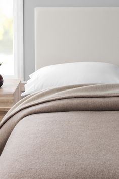 a bed with a white headboard and two nightstands in front of the window