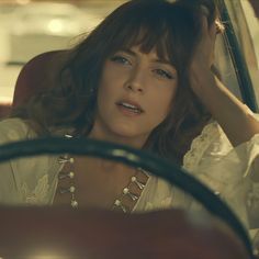 a woman sitting in the back seat of a car with her hand on her head