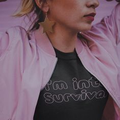 a woman wearing a pink jacket and gold star earrings with the words i'm not sorry written on it