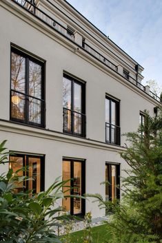 an apartment building with many windows and balconies on the second floor, surrounded by greenery