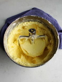 a metal bowl filled with yellow frosting on top of a table