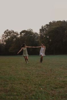 two girls are playing with a frisbee in a field at sunset or dawn