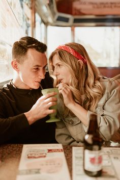 a man and woman sitting next to each other at a table with drinks in front of them