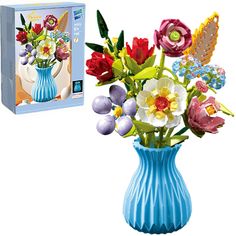 a blue vase filled with colorful flowers next to a box of puzzles on a white background