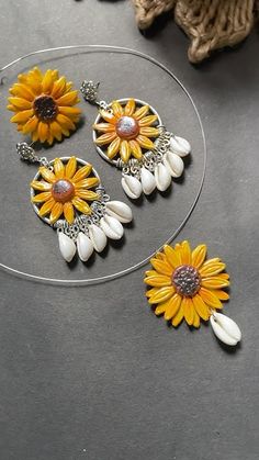 three sunflowers and shells are hanging from a necklace on a circular glass plate