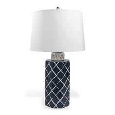 a table lamp with a white shade on the top and a blue vase underneath it